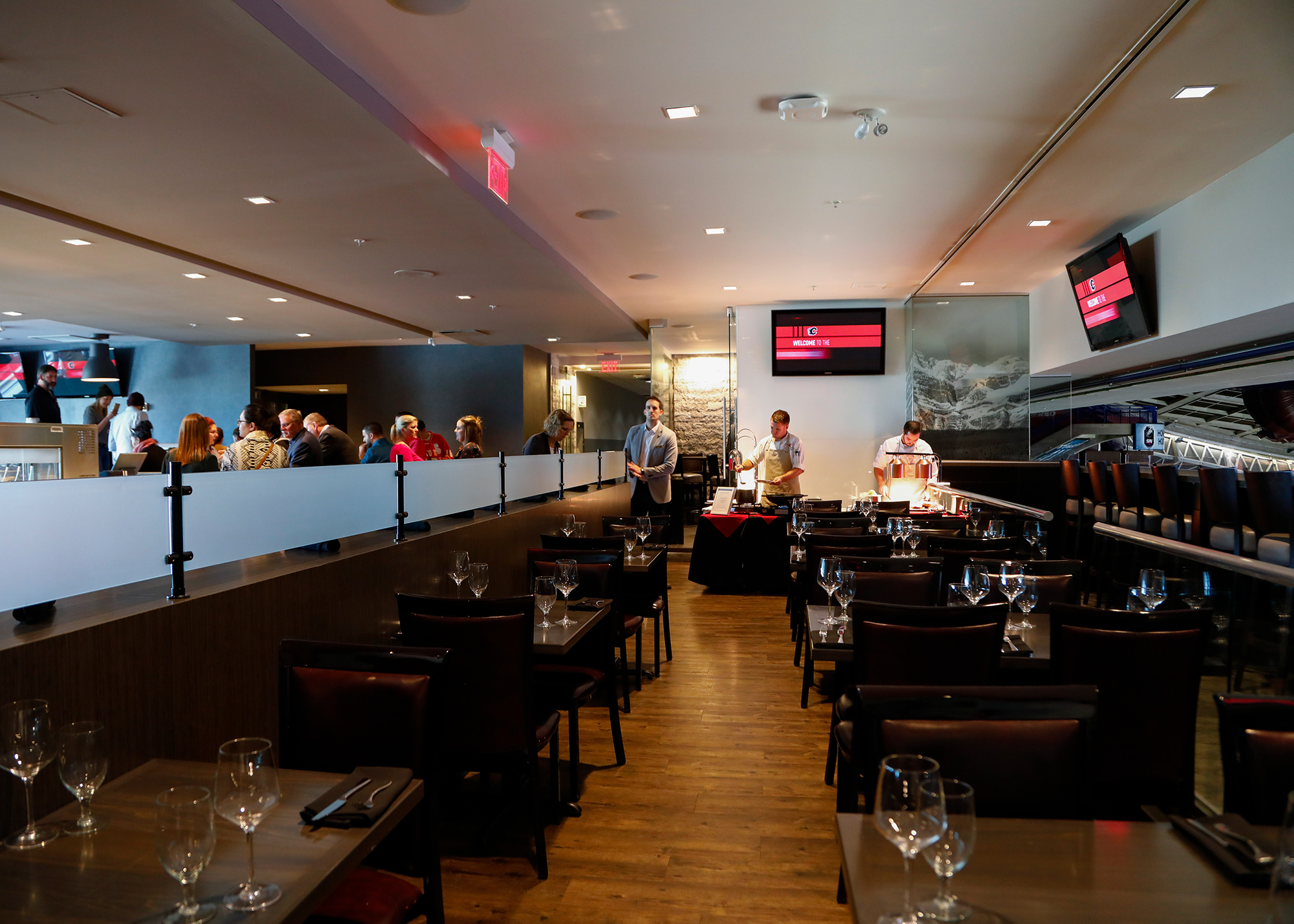 Inside the Saddleroom grill restaurant with people waiting for a table on the left and set dinner tables in the center and to the right