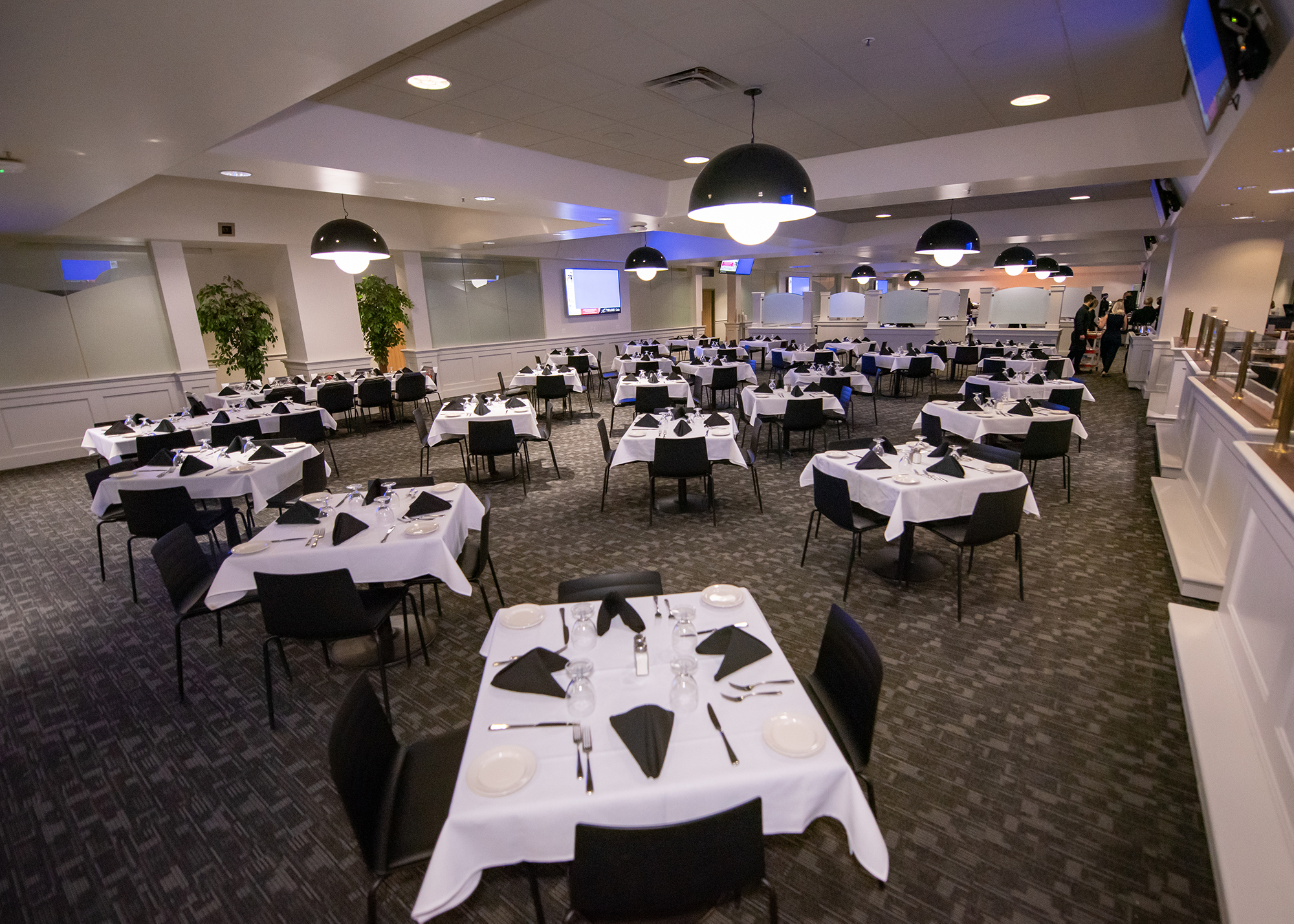 Inside the Telus Club, tables set with a white table cloth, black napkins, cutlery, plates and glasses