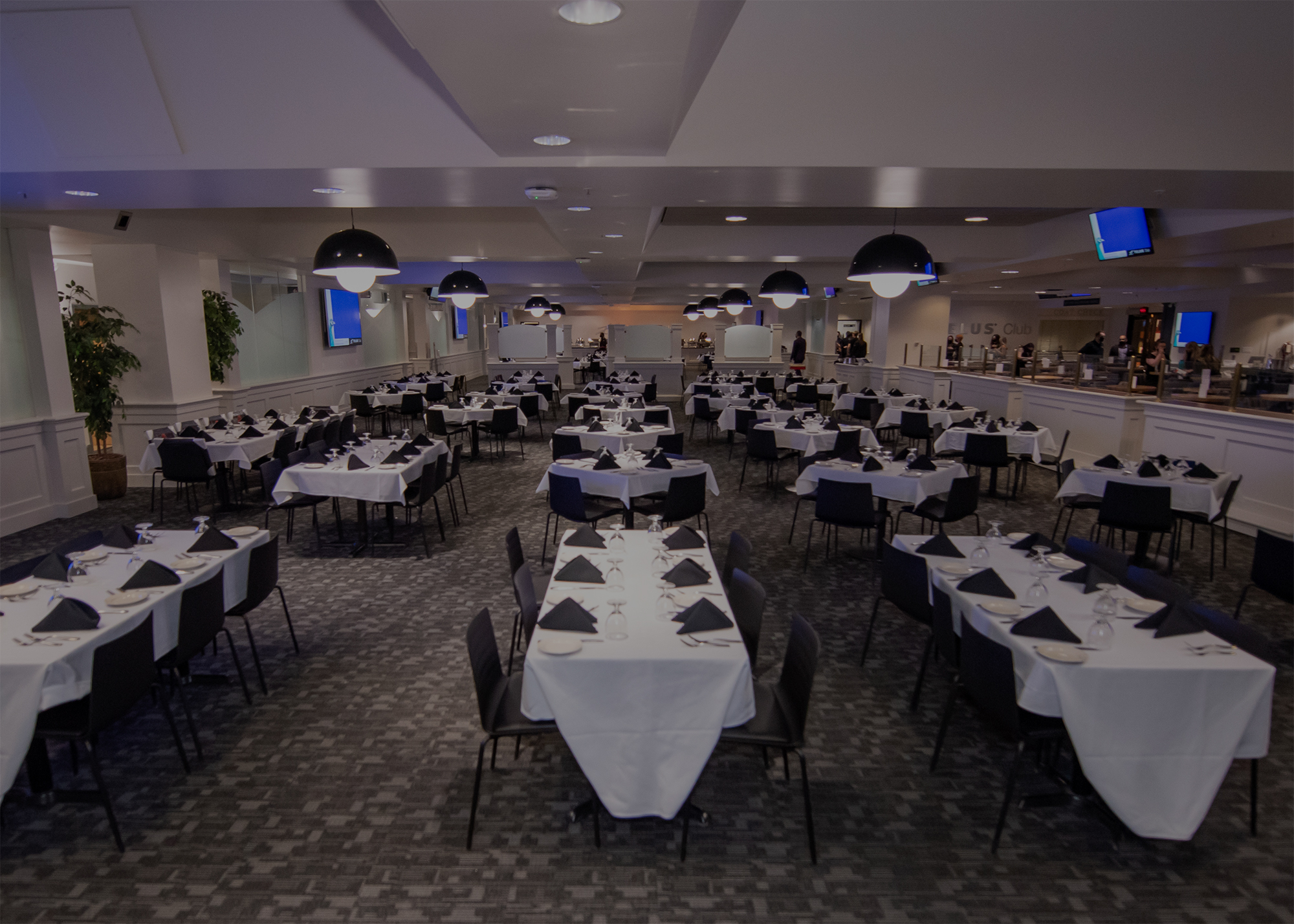 Inside the Telus Club, tables set with a white table cloth, black napkins, cutlery, plates and glasses