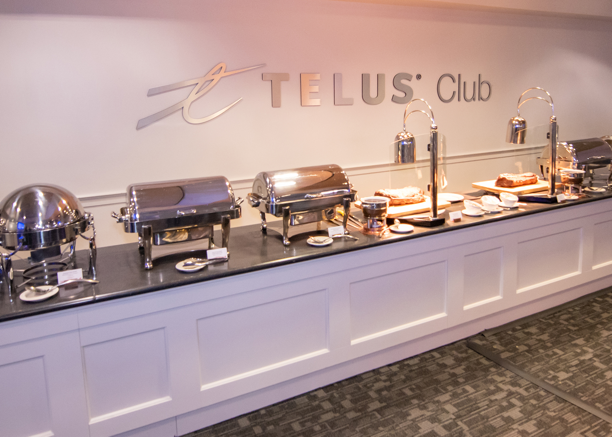 Inside the Telus Club with a buffet bar laid out in the foreground and the Telus Club logo on the wall in the background