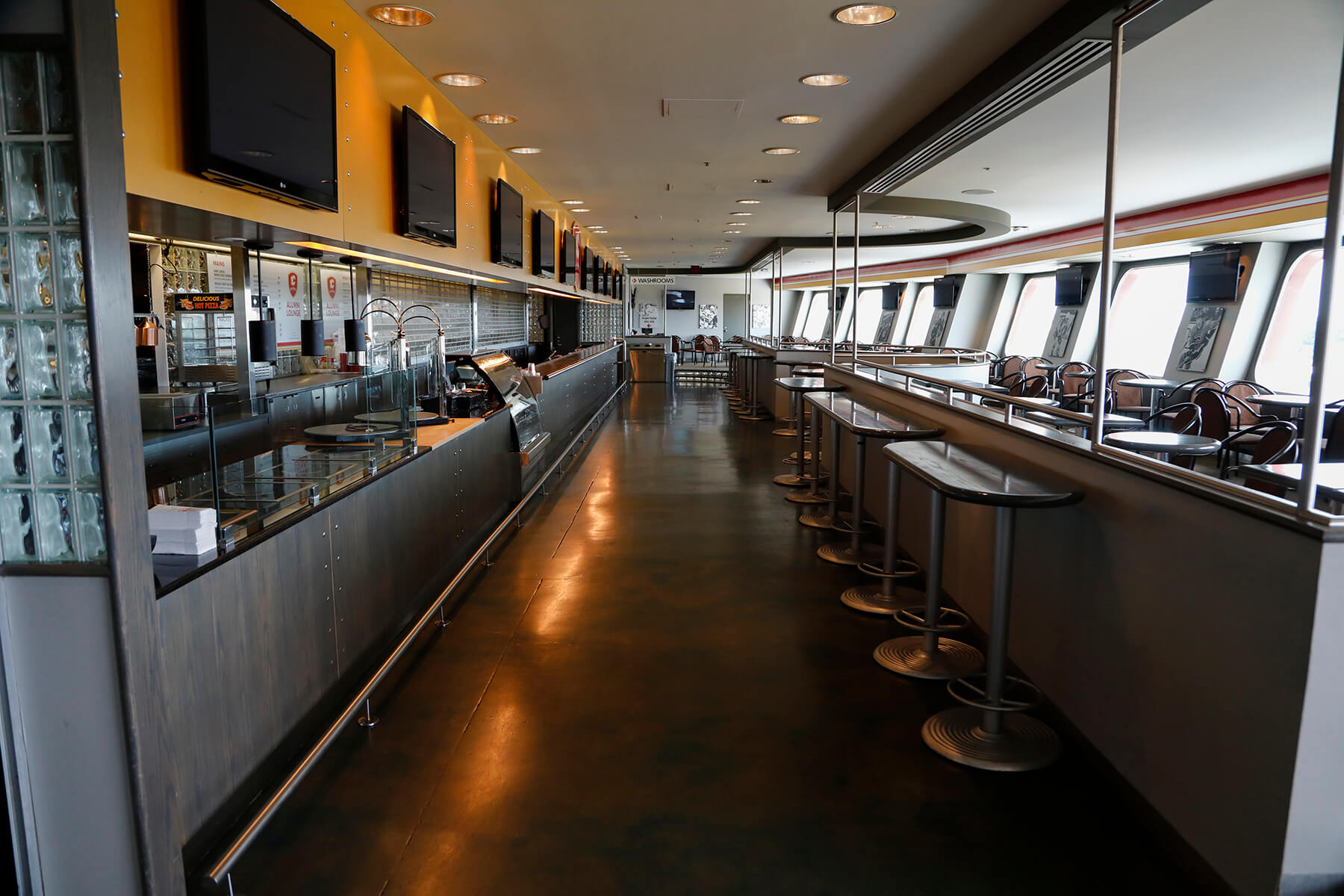 Inside the Alumni Lounge empty with the kitchen to the left and tables and chairs to the right