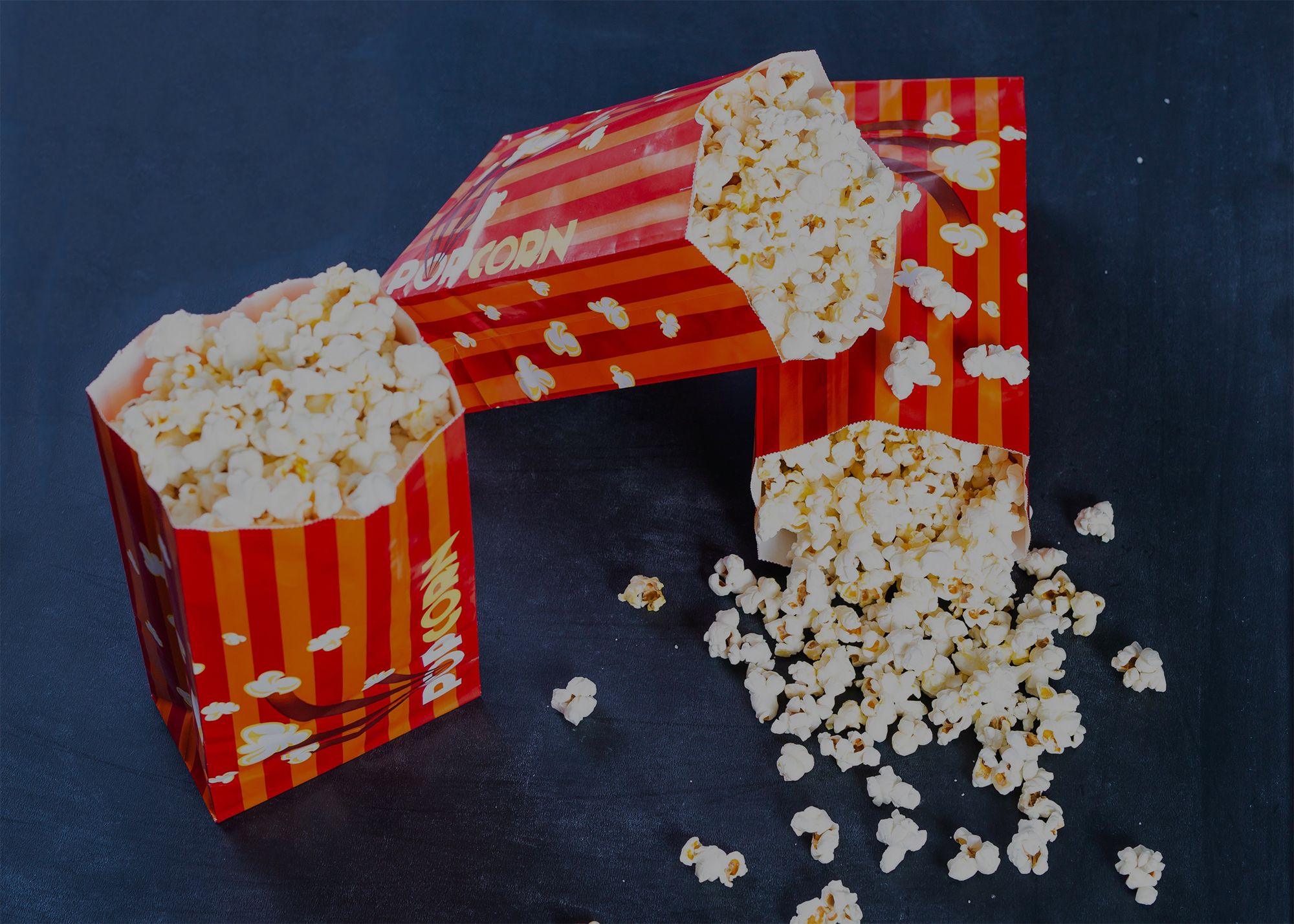 Bags of popcorn with one on it's side, popcorn spilling out of the bag